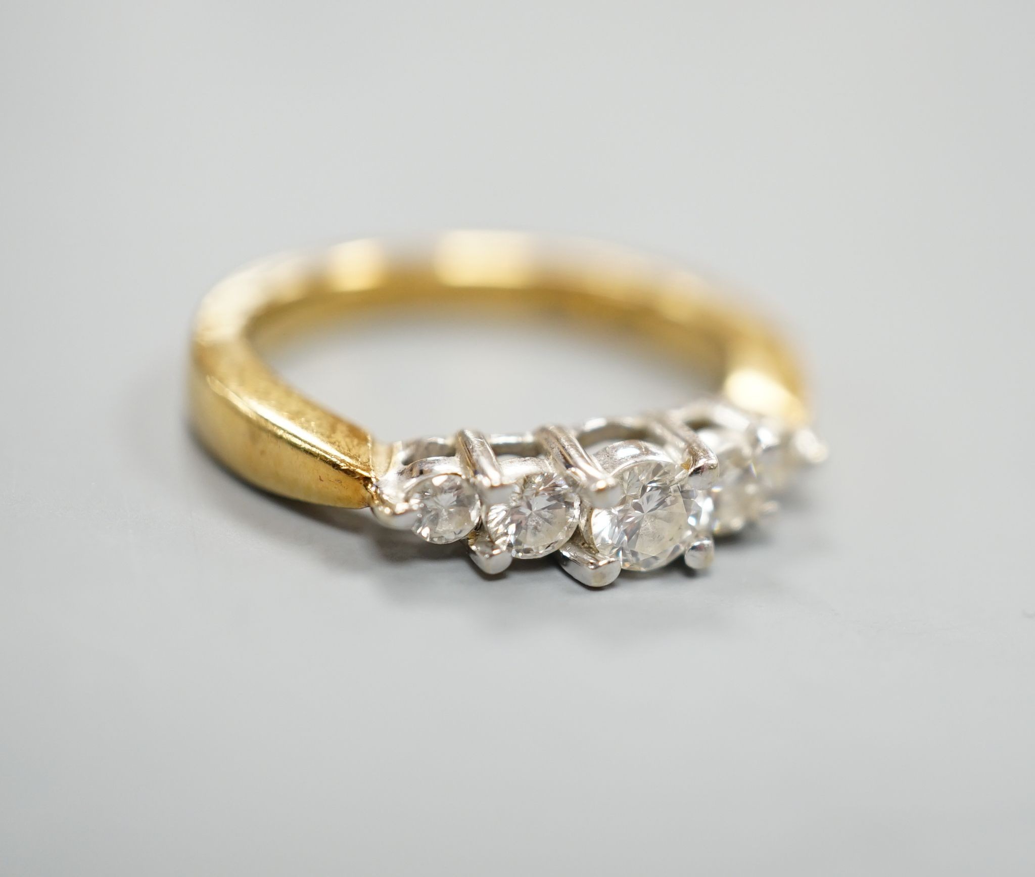 A modern 18k yellow metal and graduated five stone diamond set half hoop ring, size N, gross weight 5.4 grams.